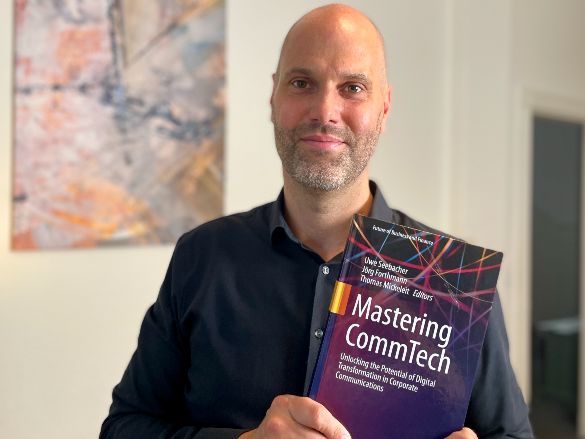 Christof Schmid zeigt das Buch Mastering CommTech bei dem er als Co-Autor mirgewirkt hat